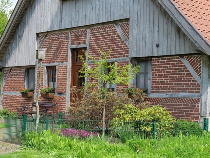 Traditional brick house with wooden elements, flower boxes and well-kept garden, marbeck,
