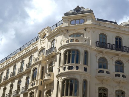 A historic building with ornate windows and wrought-iron railings under a cloudy sky, Malaga,
