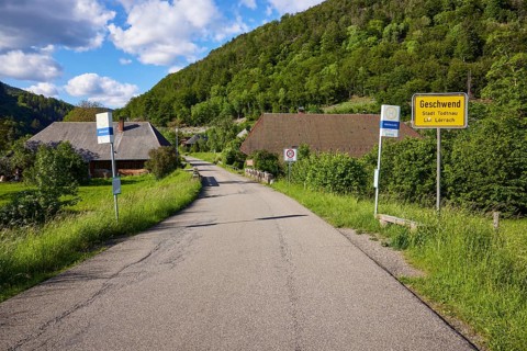 Entrance to the village with road, bus stop and village entrance sign to the Geschwend district,