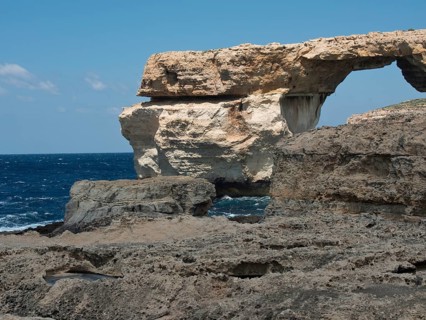 Structure formed by a rocky arch on the coast with wild sea and a rocky rugged landscape, gozo,