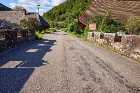 Old bridge with stone walls, flower boxes, road and Black Forest houses in the historic district of