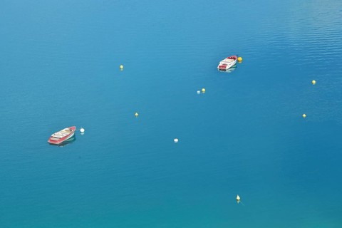 Two boats and buoys in the reservoir Lac de Sainte-Croix in the turquoise water near
