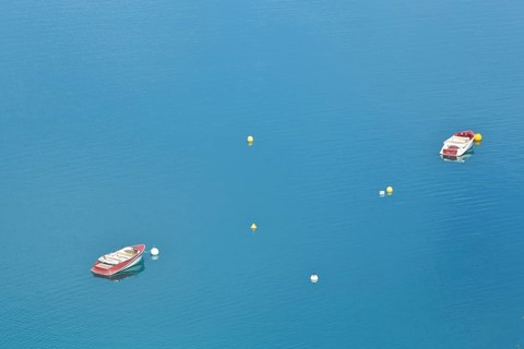 Two boats and buoys in the reservoir Lac de Sainte-Croix in the turquoise water near