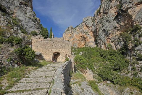 Path to Notre-Dame de Beauvoir church, archway, stone wall, rocks, mountains,