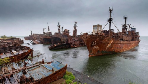 Rusty and abandoned shipwrecks in the water under dark clouds in a melancholic atmosphere, symbol