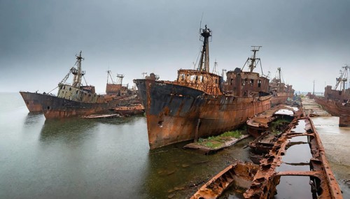 Dilapidated and rusty shipwrecks in an abandoned harbour under a grey, cloudy sky, symbol photo