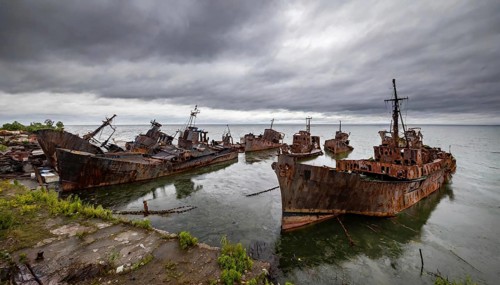 Dilapidated shipwrecks in the sea under a cloudy sky, gloomy and melancholic atmosphere, symbolic