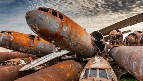 Collided and rusted aircraft wrecks on a scrap yard under a slightly cloudy sky, symbol photo, AI