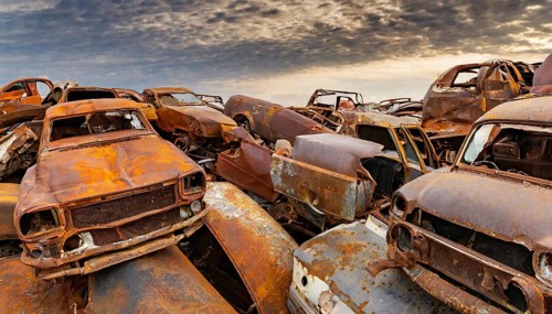 Dilapidated, rusty cars in a junkyard under an atmospheric sky at sunset, symbol photo, AI