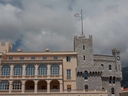 Historic castle with towers and waving flag in front of a cloudy sky, monte carlo, monaco, france
