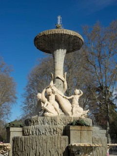 Large, artistic fountain with water jets and sculptures in the park under a blue sky, Madrid,
