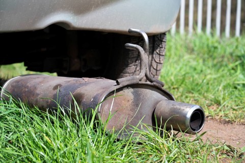 Broken exhaust and muffler of a car, rusted silencer fallen down on the road, breakdown of vehicle