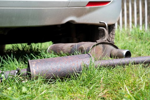 Broken exhaust and muffler of a car, rusted silencer fallen down on the road, breakdown of vehicle