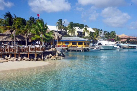 View over shallow narrow inlet channel through lagoon in front of island with sea aquarium on front