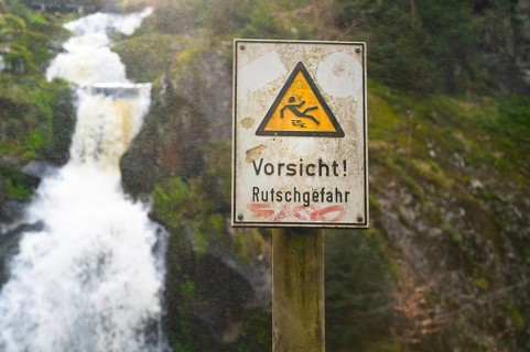 Slippery warning sign, Triberg waterfall in the Black Forest, highest fall in Germany, Gutach river