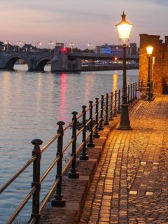 Dusk on the river bank with cobblestones and illuminated street lamp, Maastricht, limburg,