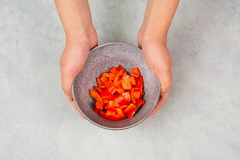 Tomatoes and red sliced pepper pieces in a bowl, prepare healthy food with paprika vegetables,