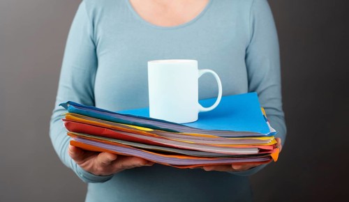 Woman with a pile of file folders and a cup of coffee, work at the office, stress and burn out,