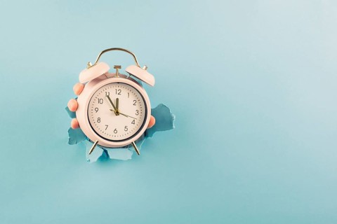 Hand holding alarm clock, torn paper hole, time management, reminder and planning, finish a