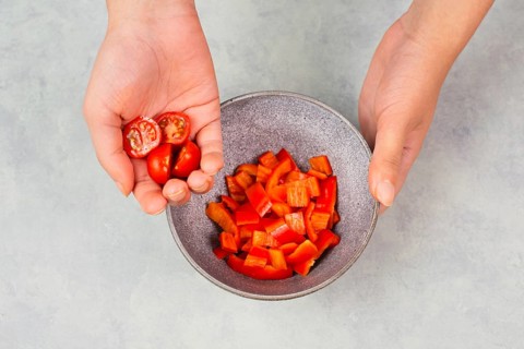 Tomatoes and red sliced pepper pieces in a bowl, prepare healthy food with paprika vegetables,