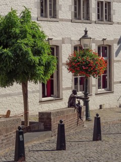 Historic town square with lantern, hanging basket, tree and a bronze sculpture, Maastricht,