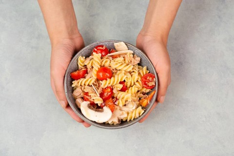 Pasta salad in a bowl, sliced mushroom, tomato, red pepper pieces and tuna, healthy food with