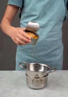Pouring oil from a tin can with preserved food, box with tuna fish, processed ingredients, feeding