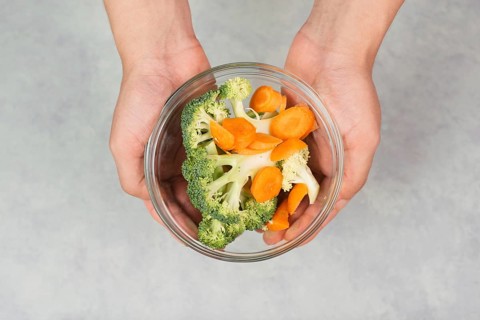 Holding fresh organic broccoli and carrots in the hand, prepare healthy food with vegetables,