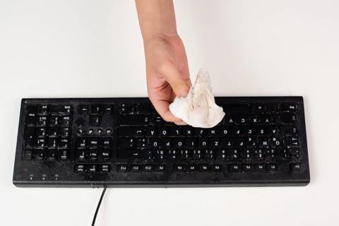Cleaning computer keyboard in office with a wet wipe rag, dusty and dirty electronic, housework