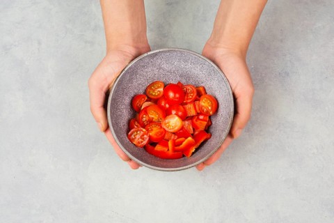 Tomatoes and red sliced pepper pieces in a bowl, prepare healthy food with paprika vegetables,