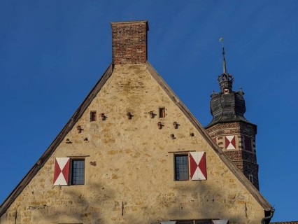 Historic building with crenellated tower and red tiled roof, under a clear blue sky, lüdinghausen,