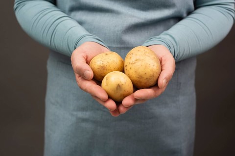 Holding fresh organic potatoes in the hand, prepare healthy food with vegetables, harvest and