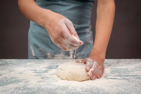 Baker kneading dough for pizza or artisan bread with his hands, prepare ingredients for food,