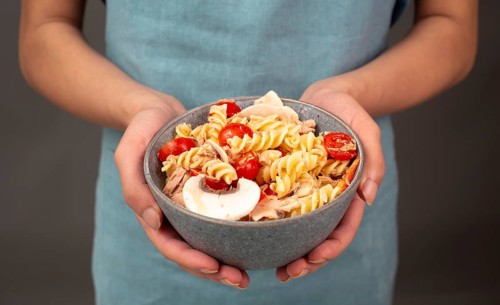 Pasta salad in a bowl, sliced mushroom, tomato, red pepper pieces and tuna, healthy food with