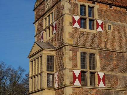 Detail of a historic castle with red and white shutters and a small tower, lüdinghausen,