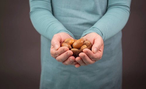 Holding a handful of nuts, mix variety of almonds, hazelnuts and pecan nuts, healthy food and