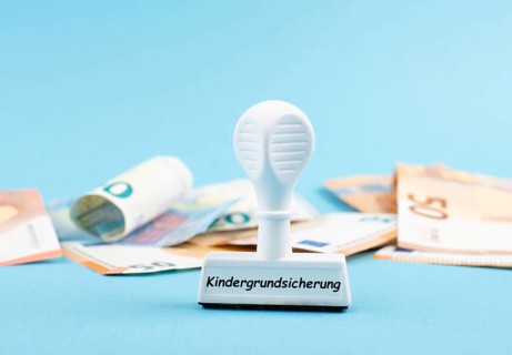 Basic child benefit stands in german language on the stamp, Euro banknotes in the background, new