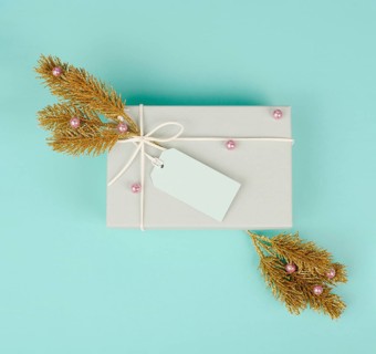 Gift box with a blank tag, golden colored fir branches and baubles, christmas holiday in winter