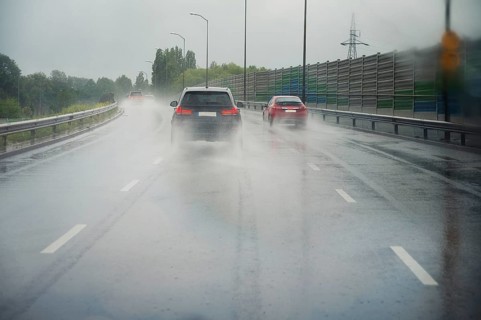 Cars driving on the road, heavy rain, low visibility, slippery street, dangerous storm, overcast