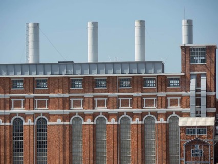 Large red brick building with several large chimneys and many windows under a blue sky, Lisbon,
