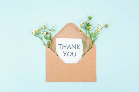 Thank you card in an envelope surrounded by flowers, being thankful, support, help and charity