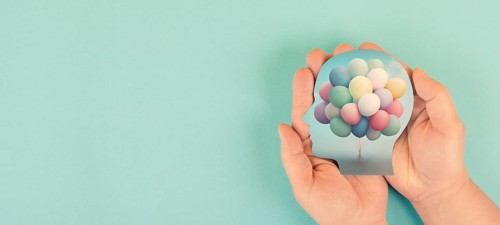 Hands holding head, brain with colorful ballons, self care, freedom and mental health concept,