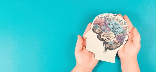 Hands holding paper head, human brain with flowers, self care and mental health concept, positive
