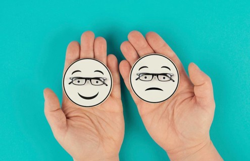 Holding a head with a sad and a happy face in the hands, mental health concept, positive and