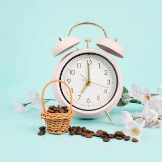 Wicker basket with roasted coffee beans, an alarm clock and cherry blossom, wake up in the morning,