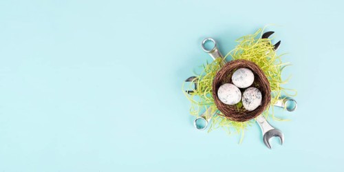 Easter eggs in a bird nest, wrenches and green grass, holiday greeting card with repair tools,