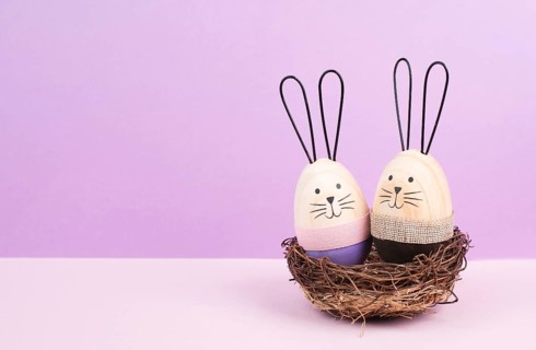 Easter bunny or rabbit couple cuddle together in a wicker nest, wooden egg, spring holiday greeting