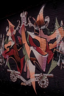 A colourful graffiti on a black brick wall with abstract shapes and a crown, Amsterdam, Netherlands