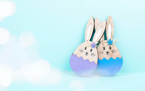 Easter bunny or rabbit couple cuddle together, wooden egg, spring holiday greeting card, bokeh