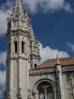 Gothic architecture of a cathedral with striking towers in front of a partly cloudy sky, Lisbon,
